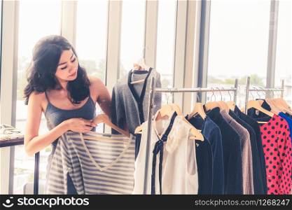 Beautiful woman shopping for clothes at retail apparel shop in the shopping mall. Modern trade lifestyle.