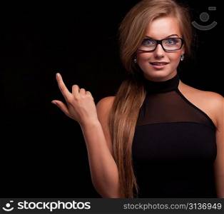 Beautiful woman showing hand on something and looking at camera isolated on black background