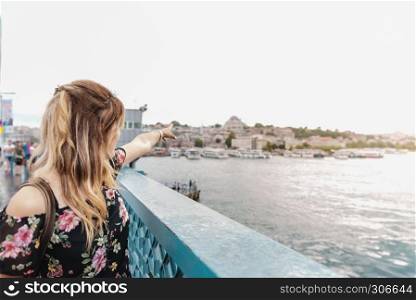 Beautiful woman shows Suleymaniye Mosque and Eminonu Town on Galata Bridge,Istanbul,Turkey. Beautiful woman travels with ferry between Asia and Europe