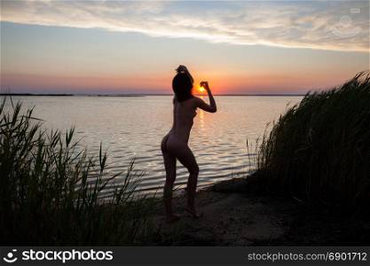 Beautiful woman silhouette at the ocean coast over sunset sky