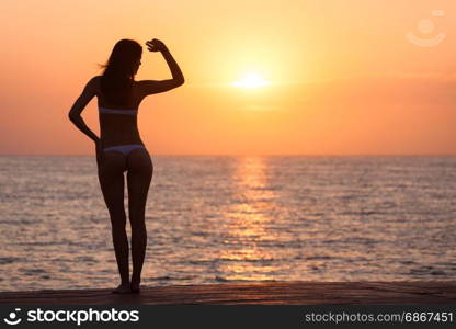 Beautiful woman silhouette over ocean sunrise background