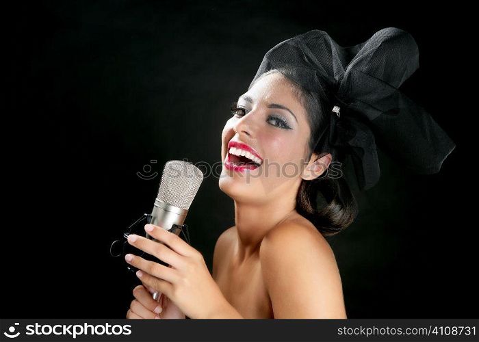 Beautiful woman singing on a vintage microphone on black background
