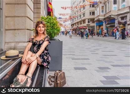 Beautiful woman sits at Istiklal street,a popular location in Beyoglu district,Istanbul,Turkey. Beautiful woman in red dress stands at Istiklal street