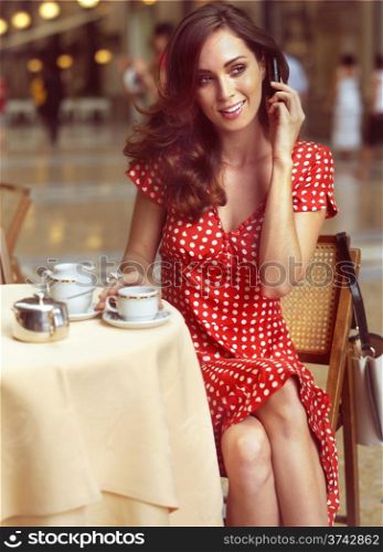 beautiful woman sitting in a Cafe and talking by mobile