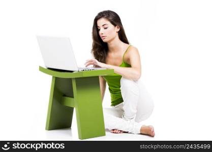 Beautiful woman sitting in the floor working with a laptop, isolated over a white