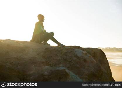 Beautiful woman sitting on a cliff over the beach
