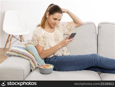Beautiful woman sitting on a sofa with her phone and texting