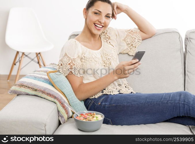 Beautiful woman sitting on a sofa with her phone and texting