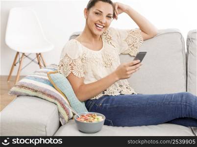 Beautiful woman sitting on a sofa with her phone and texting