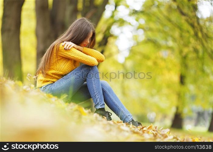 Beautiful woman sitting on autumn leaves in park