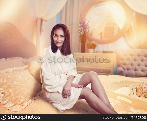 Beautiful woman sitting on bed after body treatment. Beautiful woman sitting on bed