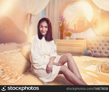 Beautiful woman sitting on bed after body treatment. Beautiful woman sitting on bed