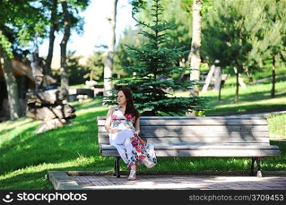 beautiful woman sitting on bench in grove . summer&acute;s day.