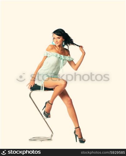 Beautiful woman sitting on chair. Full body sexy shot in fashion style. Young elegant woman in dress sit on stool. Fashion studio shot