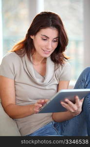 Beautiful woman sitting on couch with electronic tab