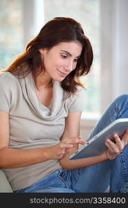 Beautiful woman sitting on couch with electronic tab