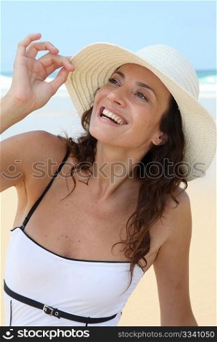 Beautiful woman sitting on the beach with straw hat