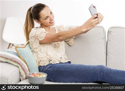 Beautiful woman sitting on the couch and taking a selfie