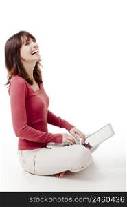 Beautiful woman sitting on the floor laughing and working with a laptop