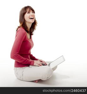 Beautiful woman sitting on the floor laughing and working with a laptop