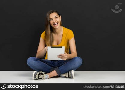 Beautiful woman sitting on the floor working with a tablet