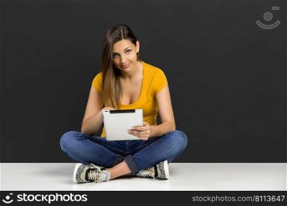 Beautiful woman sitting on the floor working with a tablet