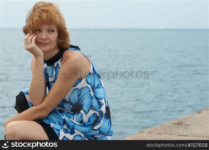 Beautiful woman sitting on the mooring with blue background