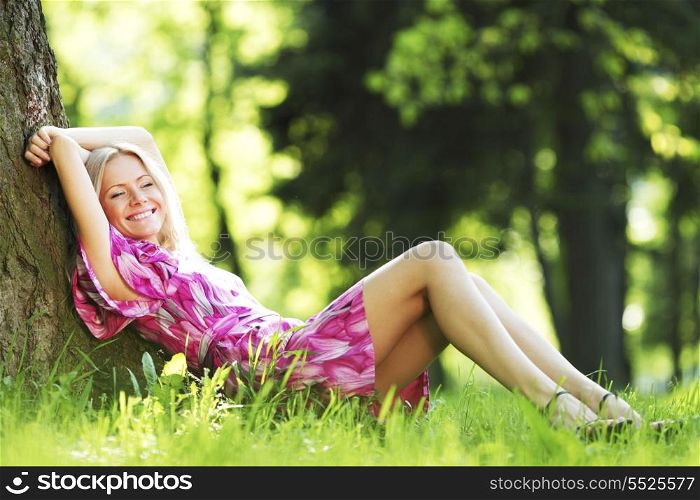Beautiful Woman sitting under tree in spring park