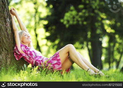 Beautiful Woman sitting under tree in spring park