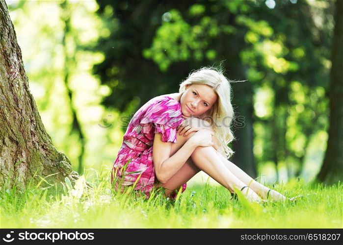 Beautiful Woman sitting under tree in spring park. Woman sitting under tree