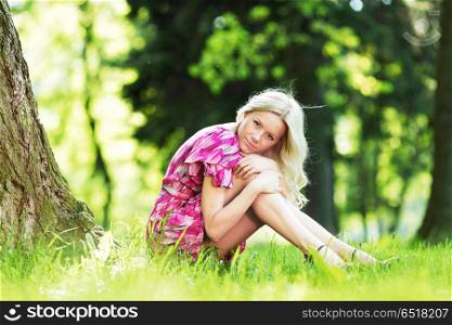 Beautiful Woman sitting under tree in spring park. Woman sitting under tree
