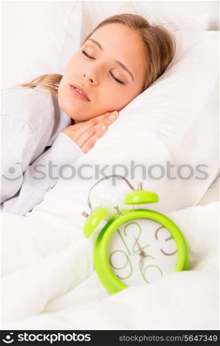 Beautiful woman sleeping with alarmclock on the bed