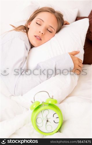 Beautiful woman sleeping with alarmclock on the bed
