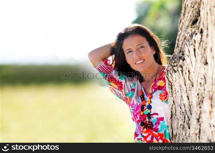 Beautiful woman standing by a tree in countryside