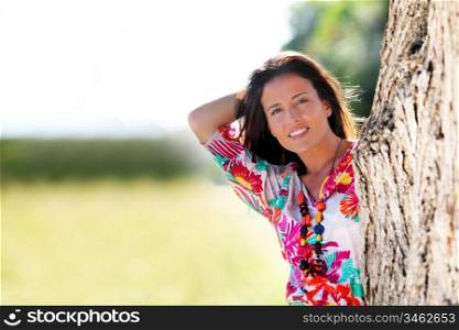Beautiful woman standing by a tree in countryside
