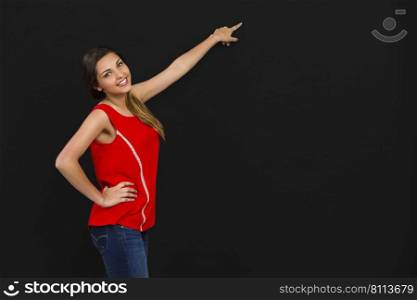 Beautiful woman standing in front of a dark board and pointing