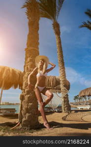 beautiful woman standing near the palm tree on the beach.. beautiful woman standing near the palm tree on the beach