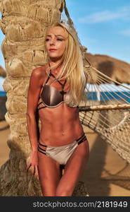 beautiful woman standing near the palm tree on the beach.. beautiful woman standing near the palm tree on the beach