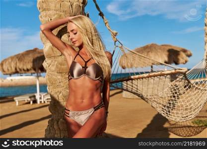beautiful woman standing near the palm tree on the beach.. beautiful woman standing near the palm tree on the beach