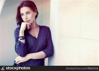 Beautiful woman standing outdoors near the building, peaceful and thoughtful female in sunlight, stylish casual look, natural beauty