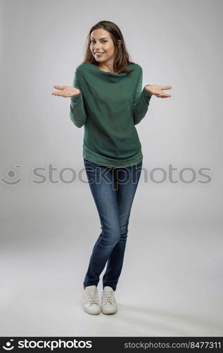 Beautiful woman standing over a gray background with arms open and smiling