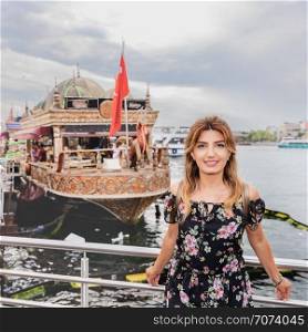 Beautiful woman stands in front of historical ships at Eminonu Town,Istanbul,Turkey. Beautiful woman travels with ferry between Asia and Europe