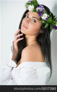 Beautiful woman supermodel wearing wreath of flowers close up portrait