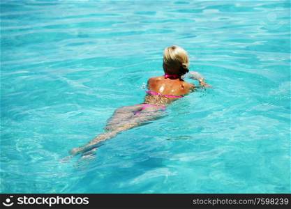 Beautiful woman swim in blue water of sea or swimming pool. Beautiful woman swimming