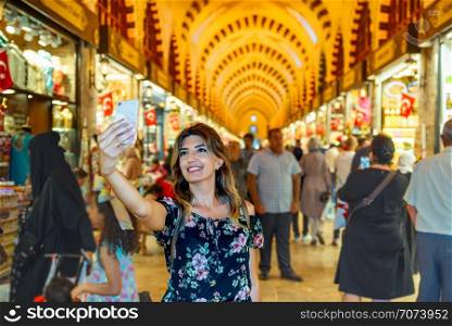 Beautiful woman takes selfie in Egypt Bazaar at Eminonu,Istanbul,Turkey. Beautiful woman looks traditional soaps in Egypt Bazaar