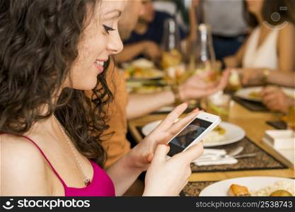 Beautiful woman taking a picture of the food at the restaurant