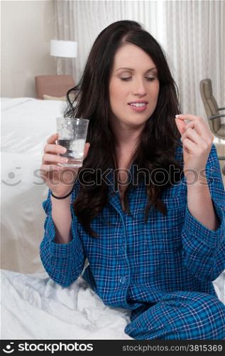 Beautiful woman taking a pill in bed