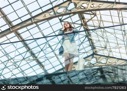 Beautiful woman talking on cellphone at airport with glass ceiling