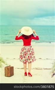 beautiful woman traveler in retro style dress on the beach
