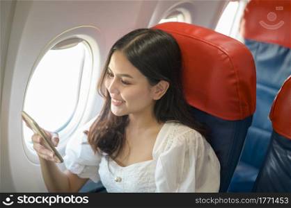Beautiful woman traveller is using smartphone on airplane
